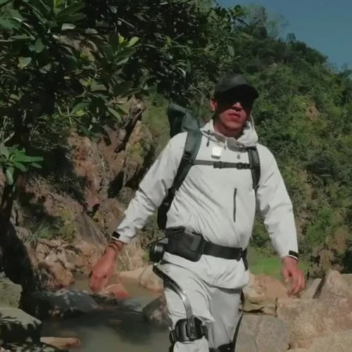 Hiker wearing the Summit hip exoskeleton crossing rocks on a trail